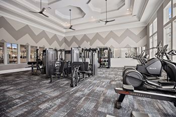 A gym with a variety of equipment including treadmills, weights, and exercise machines.